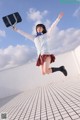 A woman in a school uniform jumping in the air.