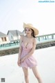 A woman in a pink dress and straw hat posing for a picture.