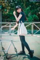 A woman standing next to a shopping cart on a tennis court.