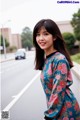 A woman in a blue dress standing on the side of a road.